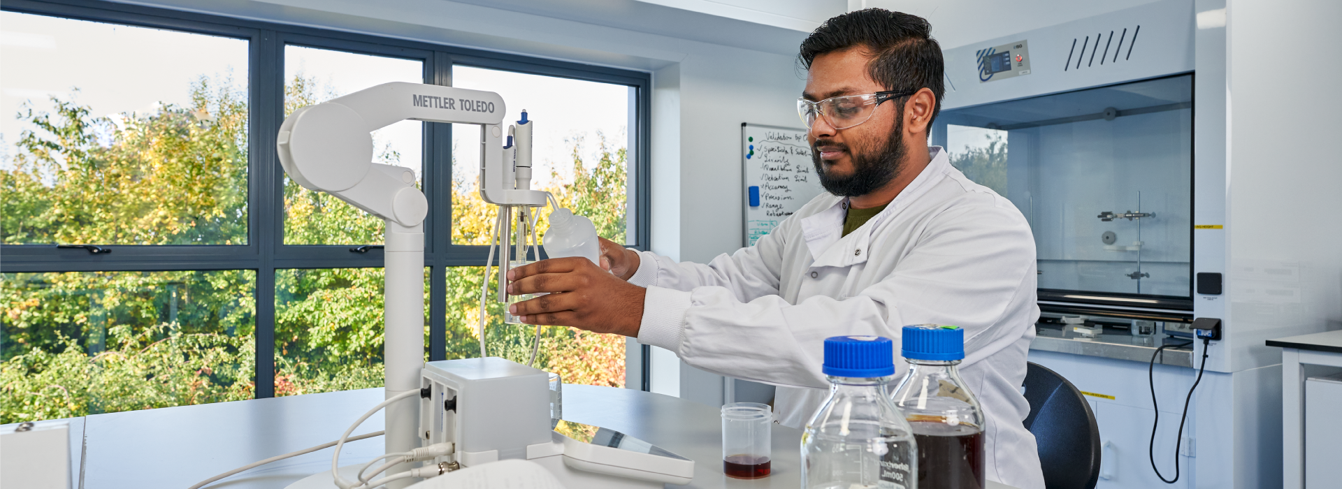 Male scientist working in a lab pouring liquid in a container.